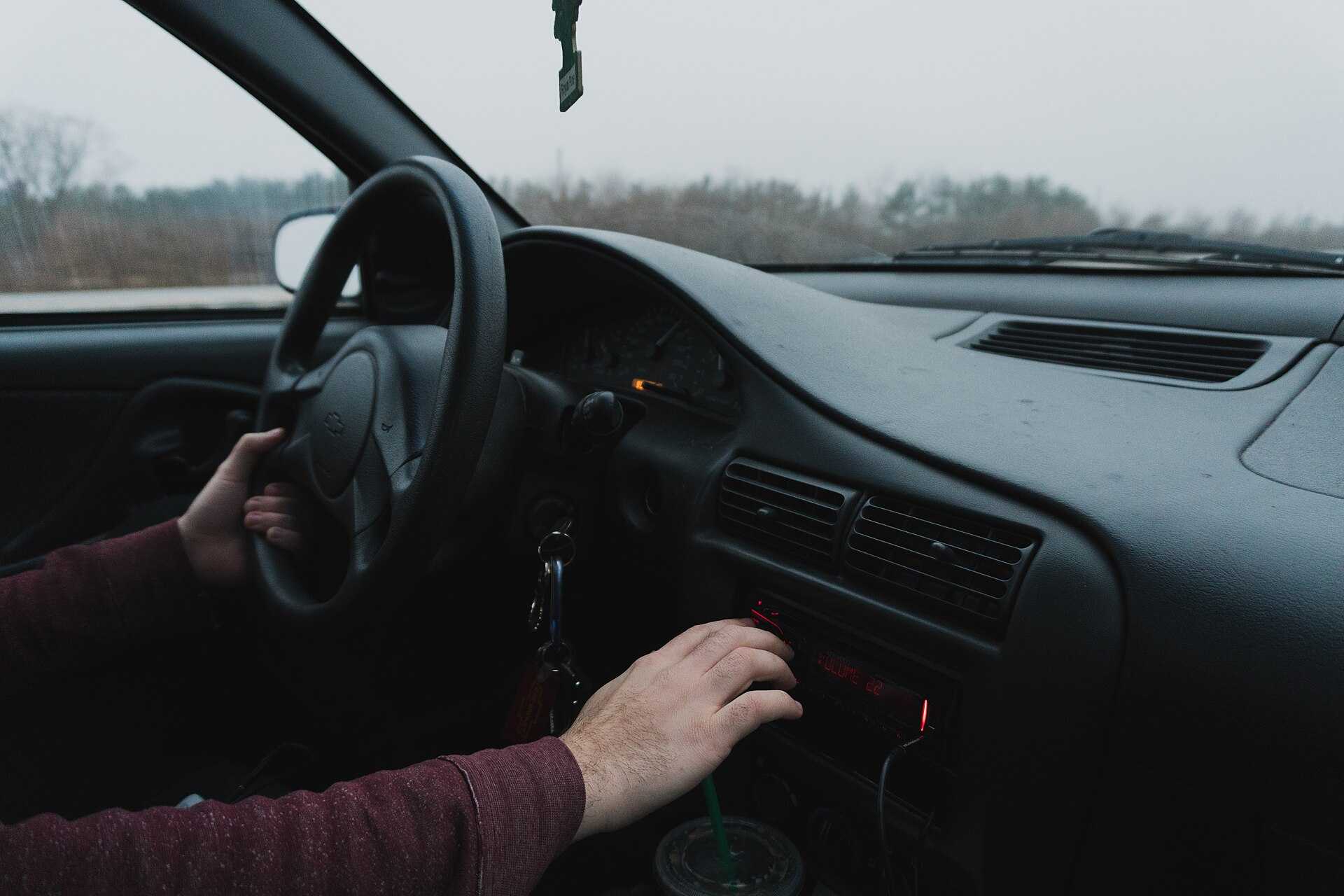 Hand tuning a car radio on the dashboard
